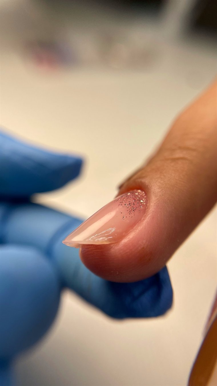 Profissional de luvas modelando alongamento em gel na unha da cliente