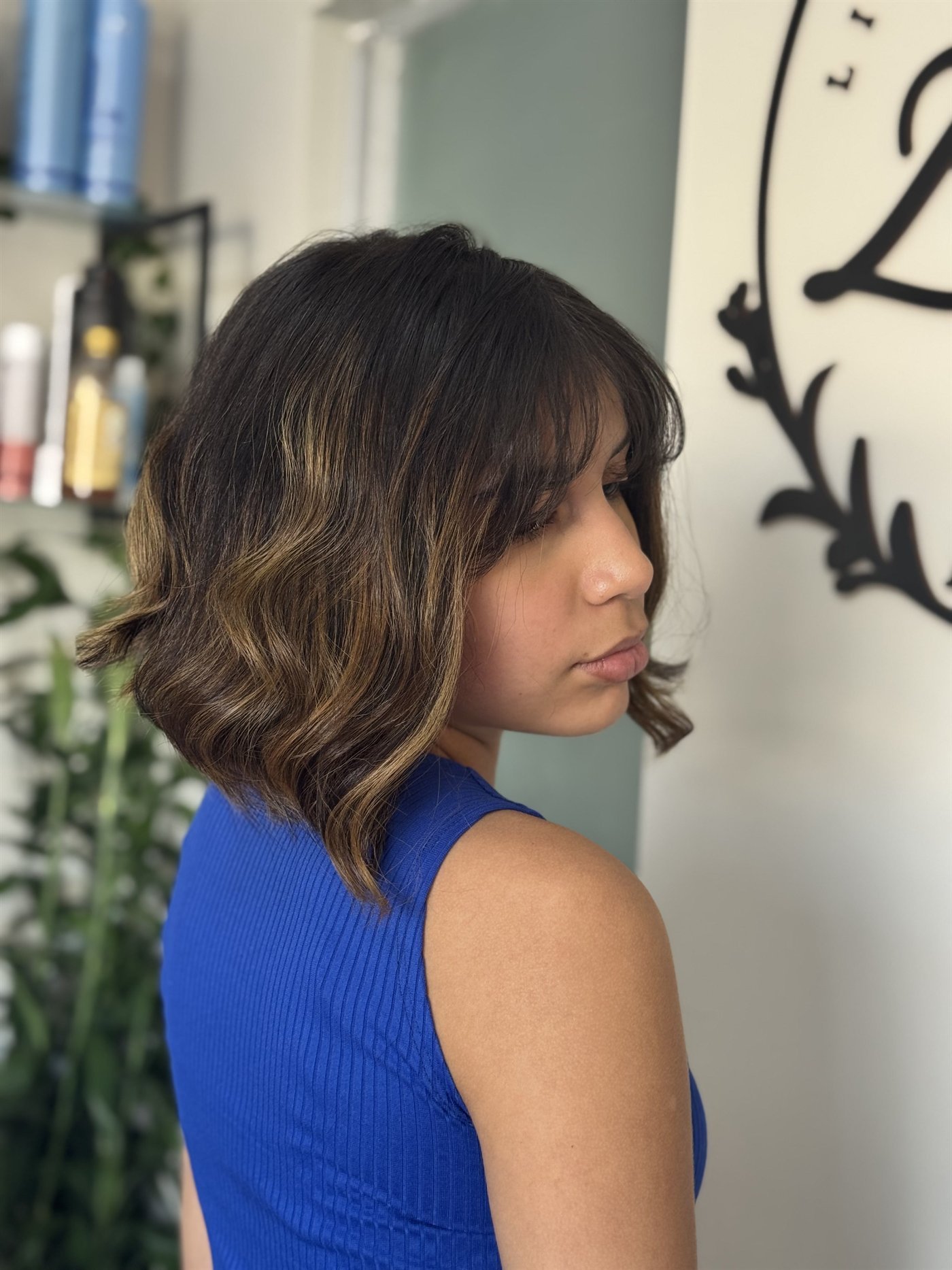 Corte na altura do ombro com franja e reflexos castanhos, de perfil