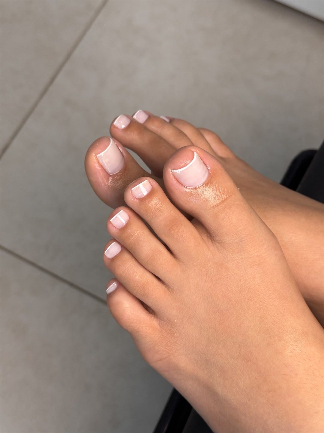 Pés com pedicure feita, unhas nude com ponta branca